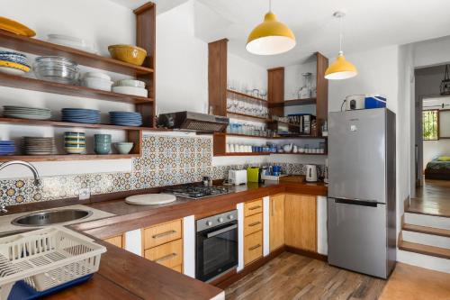 a kitchen with wooden cabinets and a stainless steel refrigerator at BlueMoon Villa - Authentic, seaside living in Trou dʼ Eau Douce