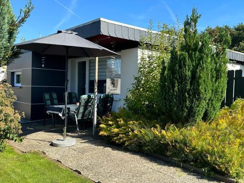 a house with an umbrella and a table and chairs at Schleibungalow Nr15 zw Ostsee und Schlei in Kappeln