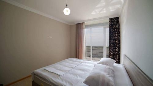 a bedroom with a white bed and a window at Seaside cottages in Chakvi