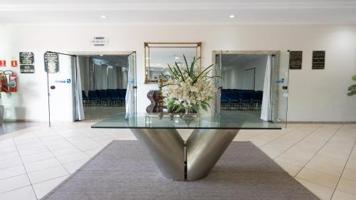 a glass table in a lobby with a vase of flowers at Hotel Dan Inn Franca & Convenções By Nacional Inn in Franca