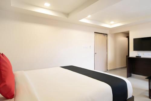 a bedroom with a white bed and a flat screen tv at Capital O Seatree in Visakhapatnam