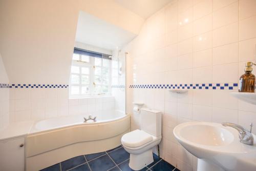 a bathroom with a tub and a toilet and a sink at Tower Cottage, Walberswick in Walberswick