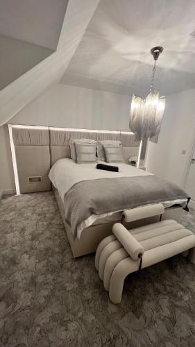 a white bedroom with a large bed and a chair at San Pedro Luxury Sittingbourne in Kent