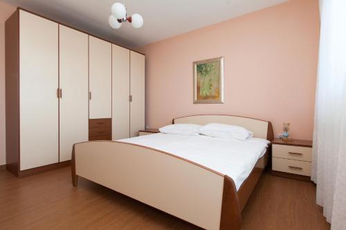 a bedroom with a white bed and white cabinets at Apartment Anne in Crikvenica