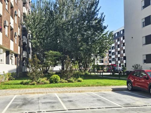 a red car parked in a parking lot next to buildings at Square Garden 32 in Novi Sad