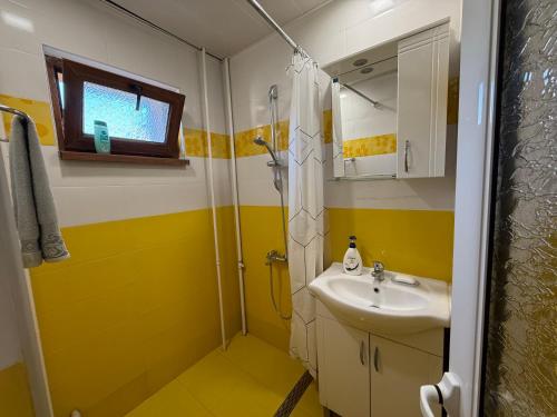 a yellow and white bathroom with a sink and shower at Central apartments Pleven in Pleven