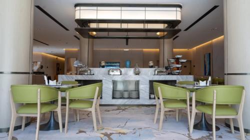 a dining room with green chairs and a fireplace at فندق روزا جراند غرناطه in Riyadh