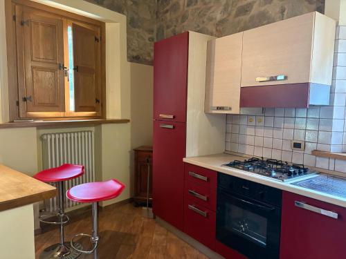 a kitchen with red cabinets and red stools at La casa di Bianca b&b in Collagna
