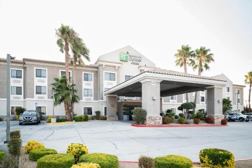 a hotel building with a parking lot and palm trees at Holiday Inn Express Hotel & Suites Hesperia by IHG in Hesperia