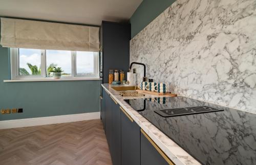 a kitchen with a marble counter top and a window at Priory Bay Escapes - Alba in Tenby