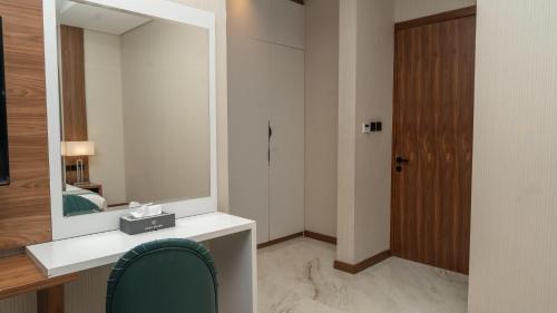 a bathroom with a vanity with a mirror and a chair at Rosa Grand Hotel in Riyadh