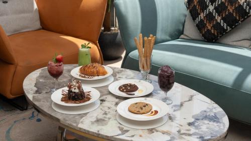 a table with plates of desserts and drinks on it at Rosa Grand Hotel in Riyadh