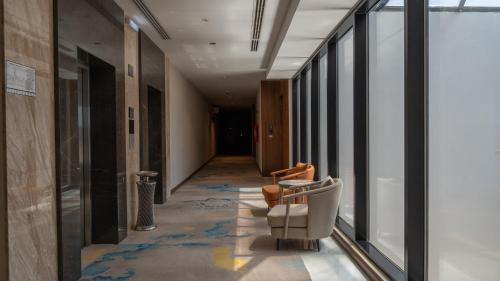 a corridor with a chair and a hallway with windows at Rosa Grand Hotel in Riyadh