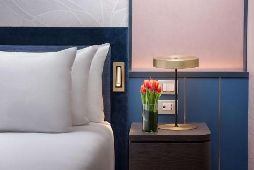 a vase of flowers on a table next to a bed at NH Collection Genova Marina in Genova