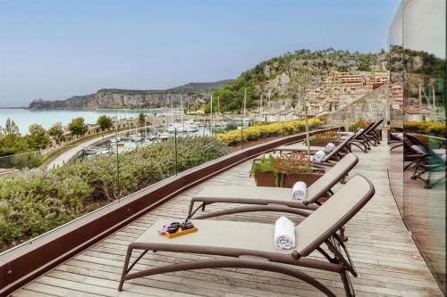 a row of lounge chairs on a balcony overlooking the water at Tivoli Portopiccolo Sistiana Apartments in Sistiana