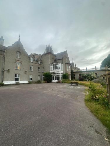 a large building with a parking lot in front of it at Cluny Hill Hotel in Forres