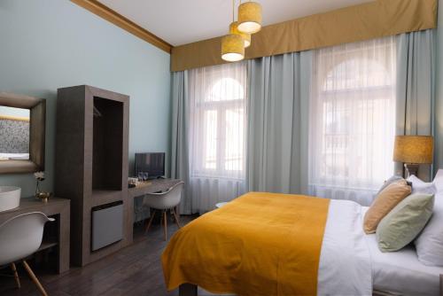 a bedroom with a bed and a desk and a television at Salvatore Prague Rooms in Prague