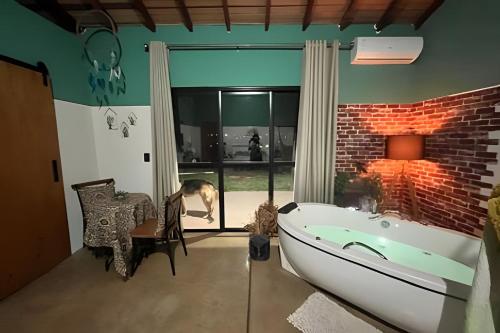 a bathroom with a tub and a dog looking out the window at Chalé Cabana Studio - Louveira Jundiaí Vinhedo 01 in Jundiaí