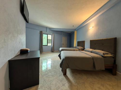two beds in a room with blue walls at hotel hao han in Ciudad Hidalgo