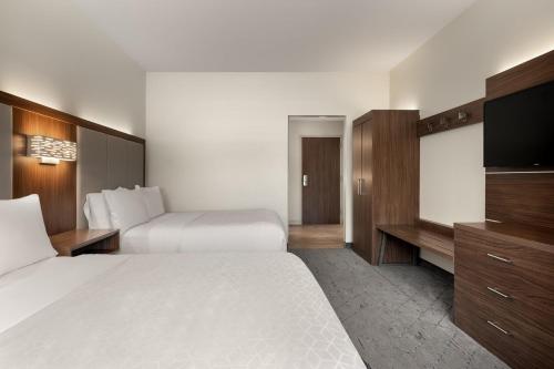 a hotel room with two beds and a flat screen tv at Holiday Inn Express Queensbury-Lake George Area by IHG in Queensbury
