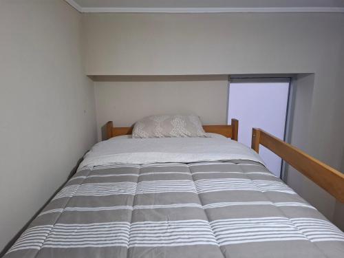 a large bed in a small room with a window at Bonito Departamento con estacionamiento, vista a parque y estadio nacional, muy tranquilo in Lima
