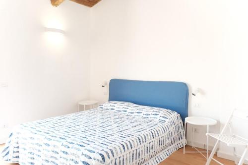 a bed in a white room with a blue headboard at The Wonder 400m from the Sea in Scario