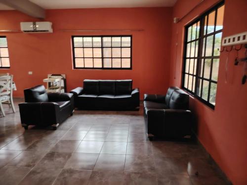 a living room with black couches and orange walls at Casa Familiar in Homún