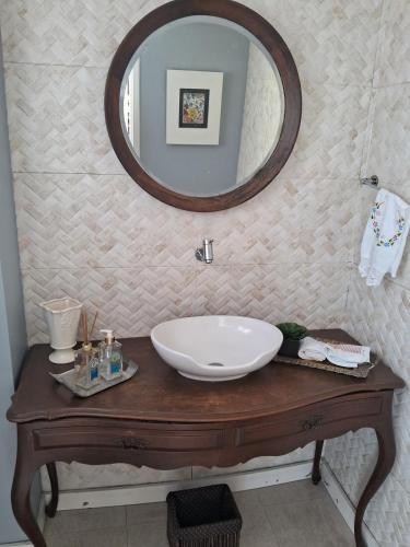 a bathroom with a sink and a mirror on a table at Casa Familiar em Teresópolis RJ in Teresópolis