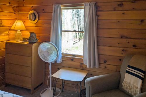 a room with a window and a chair and a fan at Birch Grove Cabin in Fort Edgecomb