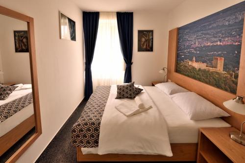 a bedroom with a white bed with a large window at Hotel Orient Zagreb in Zagreb