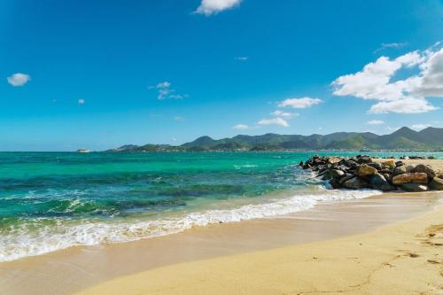 a beach with a group of rocks and the ocean at Villa plage piscine terrasse privée citerne de sécurité in Baie Nettle
