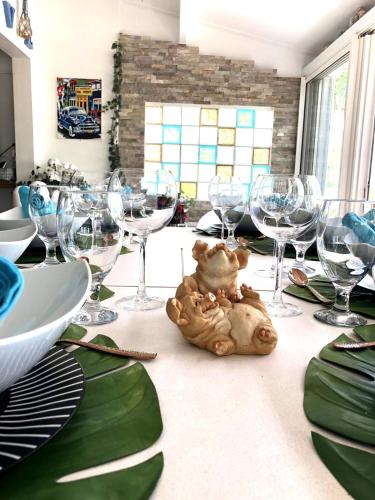 a table with wine glasses and a teddy bear on it at Villa plage piscine terrasse privée citerne de sécurité in Baie Nettle
