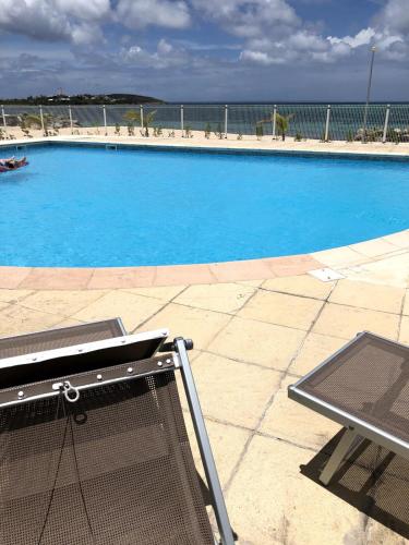 a large blue swimming pool with a laptop in front of it at Villa plage piscine terrasse privée citerne de sécurité in Baie Nettle