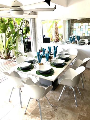 a dining room table with chairs and a white table and chairsktop at Villa plage piscine terrasse privée citerne de sécurité in Baie Nettle