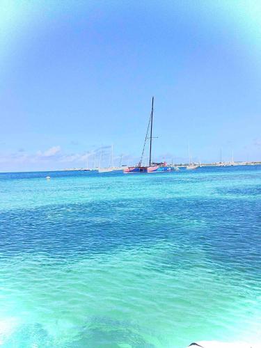 a sail boat in the water with a boat in the distance at Villa plage piscine terrasse privée citerne de sécurité in Baie Nettle