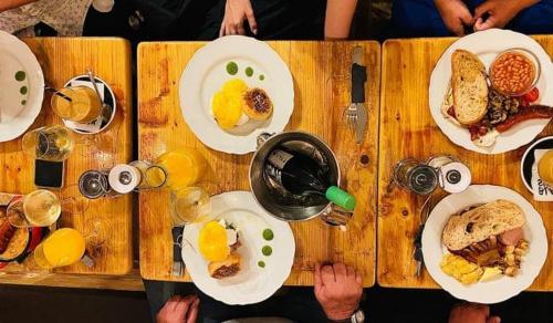 a wooden table topped with plates of breakfast food at Jégmadár Apartman in Gyula