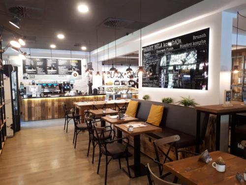 a restaurant with wooden tables and chairs and a bar at Jégmadár Apartman in Gyula