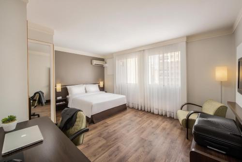 a hotel room with a bed and a desk and a table at Intercity São Paulo Nações Unidas in Sao Paulo