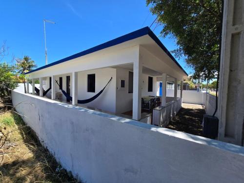 サン・フランシスコ・デ・イタバポアナにあるCasa de praia pet friendly muito aconchegante a dois minutos da praia!のコンクリートの壁の後ろにある小さな白い建物