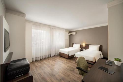 a hotel room with two beds and a desk at Intercity São Paulo Nações Unidas in Sao Paulo
