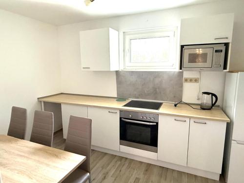 a kitchen with white cabinets and a table and a microwave at Monteurwohnung in Siegen in Wilnsdorf