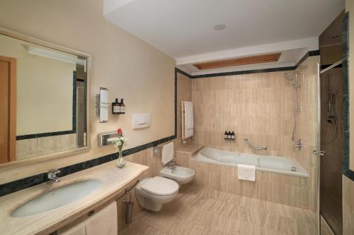 a bathroom with a tub and a toilet and a sink at NH Collection Genova Marina in Genova