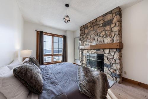 a bedroom with a stone fireplace and a bed with pillows at Ski in - Ski out Condo, Hot Tub, Fireplace, Parking, Lake View in Mont-Tremblant