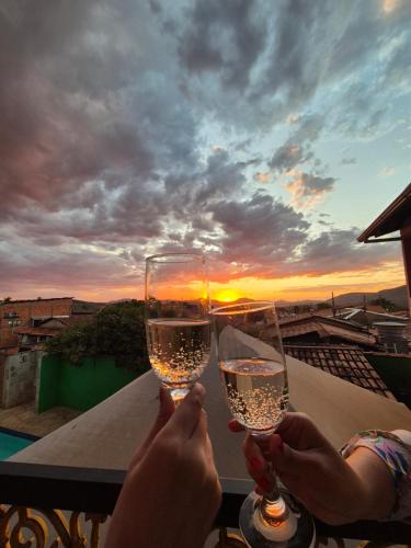dos personas sosteniendo copas de vino en un balcón en Pousada 600 Metros Centro Histórico Antiga Pousada Casebre Piscina Ar Condicionado, en Pirenópolis