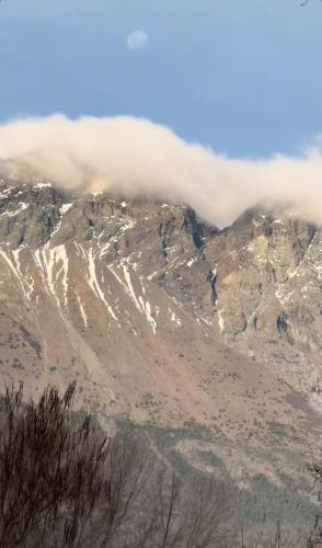 a mountain with a layer of clouds on top of it at Rest in the mountains in El Bolsón