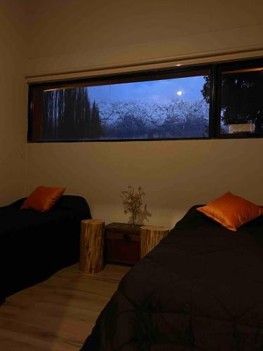 a bedroom with two beds and a large window at Rest in the mountains in El Bolsón