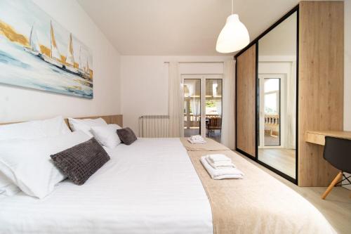 a bedroom with a large white bed and a desk at Apartments Spomenka in Mundanije