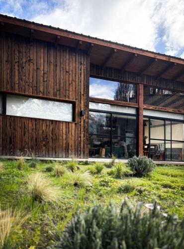 a wooden house with large windows and a yard at Rest in the mountains in El Bolsón