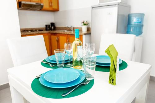 a white table with blue plates and a bottle of wine at SOL CARIBE VILLAGE - STUDIOS DELUXE - playa LOS CORALES in Punta Cana