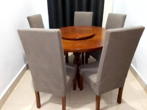 a wooden dining room table with four white chairs at Volcano homes in Ruhengeri